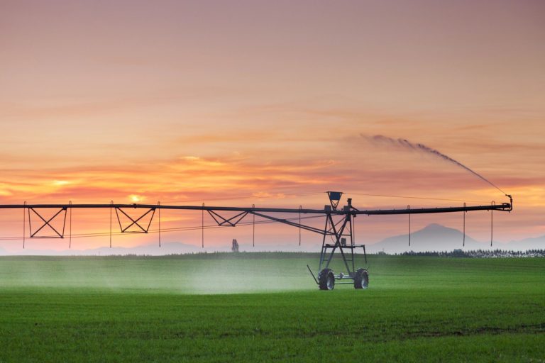 irrigation pivot running in field at sunset